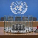 Sala de prensa de la ONU con barreras transparentes que contienen nodos de agentes de IA