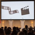 Escenario de la Cumbre Lumière con pantalla de cine, claqueta, atriles y banderas de Francia y Corea del Sur