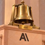 Campana bursátil junto al emblema de Anthropic en una escena editorial de salida a bolsa