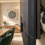 Grabadora oculta detrás de un televisor en una oficina identificada con el logo de OpenAI, en una recreación editorial